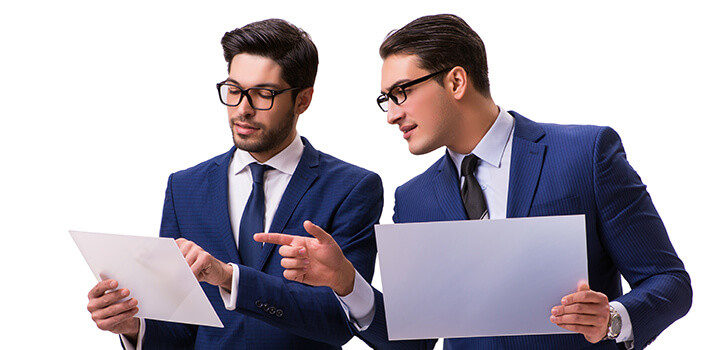タブレットを見ながら会話を交わすビジネスマン2人の画像