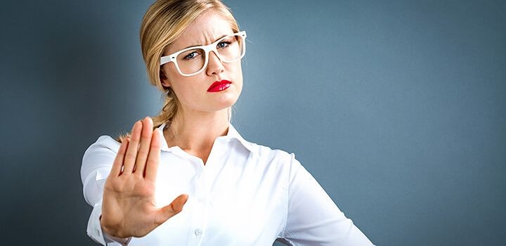 右手の手のひらをこちらに向け、不満気な表情をしている女性の画像