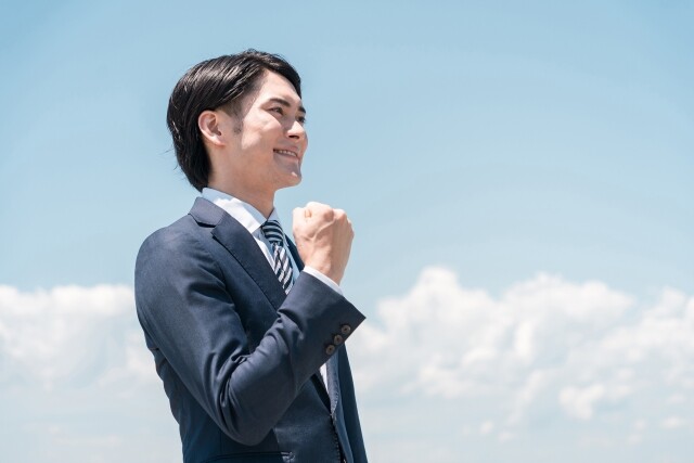青空の下でガッツポーズする男性