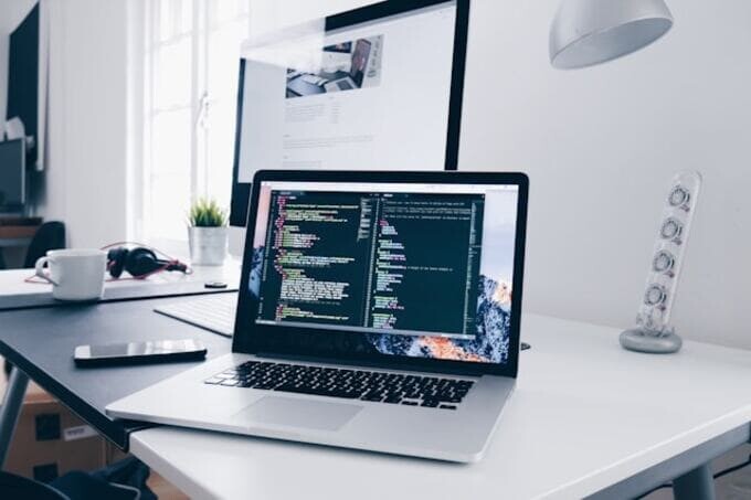机の上で画面にコード行が表示されているmacbook