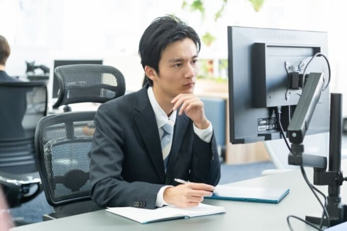 モニターを見て勉強するスーツの男性