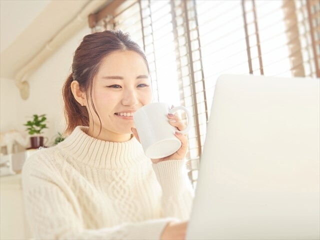 マグカップを持ってパソコンを見る女性