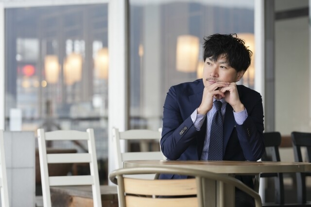 カフェで考え事をするスーツ姿の男性